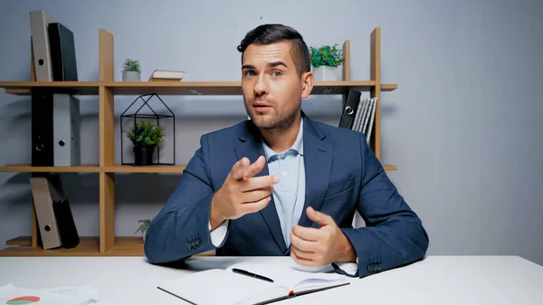 Geschäftsmann zeigt mit erhobenem Zeigefinger auf Tisch — Stockfoto