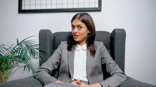 Manager in giacca e cravatta sorridente durante la video chat in ufficio — Foto stock