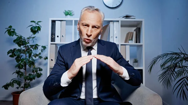 Сірий волохатий бізнесмен розмовляє і жестикулює під час відеодзвінка в офісі — стокове фото