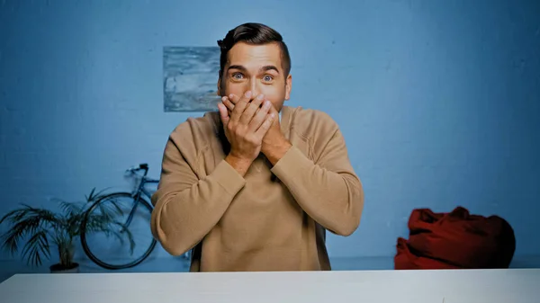 Homme excité couvrant la bouche avec les mains à la maison — Photo de stock