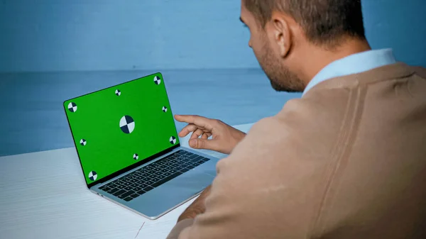 Laptop com chave chroma perto do homem apontando com o dedo em primeiro plano desfocado — Fotografia de Stock
