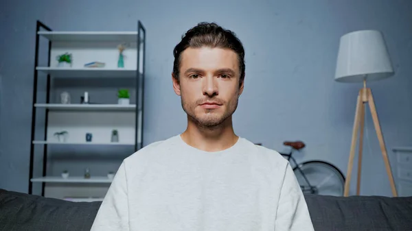 Brunette man looking at camera in living room — Stock Photo