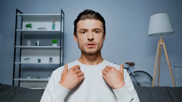 Молодий чоловік вказує на себе, маючи відеочат вдома — стокове фото