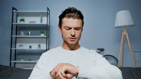 Man in jumper looking at hand at home — Stock Photo