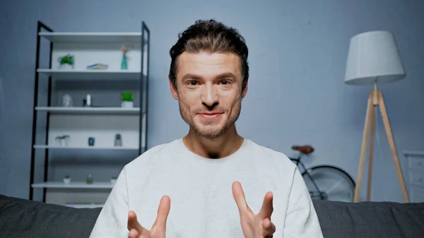 Fröhlicher Mann im Pullover gestikuliert bei Videoanruf zu Hause — Stockfoto