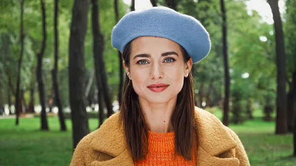 Young woman in fashionable beret looking at camera in autumn park — Stock Photo