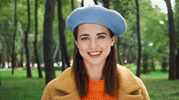 Femme heureuse dans des vêtements d'automne élégants souriant à la caméra dans le parc — Photo de stock