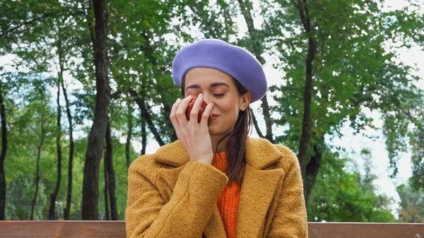 Довольная женщина нюхает спелое яблоко с закрытыми глазами в парке — стоковое фото