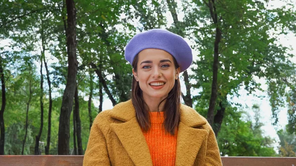 Весела жінка в модному вбранні дивиться на камеру в осінньому парку — стокове фото
