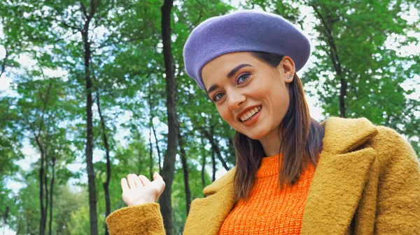 Femme souriante pointant avec la main tout en regardant la caméra dans le parc — Photo de stock