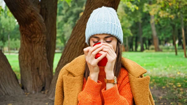 Giovane donna in abito autunnale godendo aroma di mela matura nel parco — Foto stock