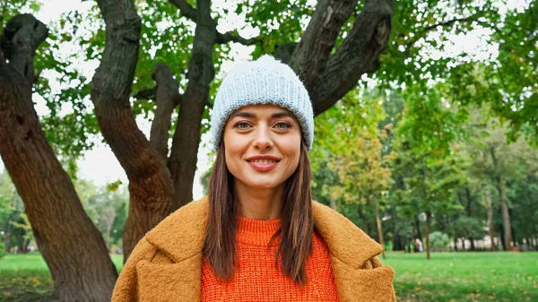 Mujer alegre en ropa elegante mirando a la cámara en el parque de otoño - foto de stock