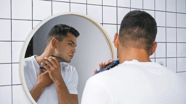 Mann in weißem T-Shirt rasiert Hals mit Rasiermesser in der Nähe Spiegel im Badezimmer — Stockfoto