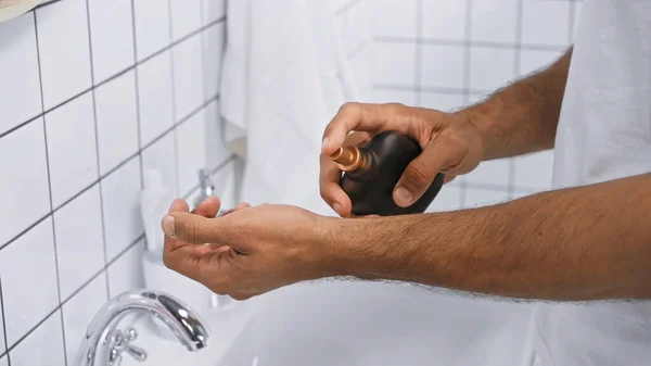 Vista cortada do homem aplicando perfume na mão no banheiro — Fotografia de Stock