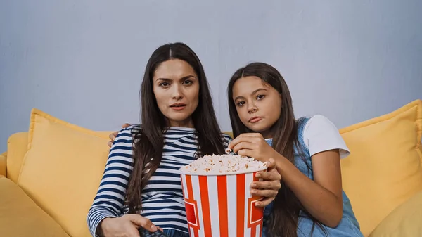 Mãe e filha assistindo filme perto de balde com pipoca — Fotografia de Stock