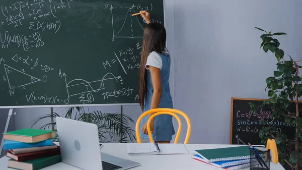 Visão traseira da menina escrevendo gráfico matemático no quadro — Fotografia de Stock