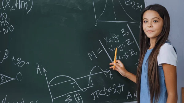 Caneta de retenção para crianças enquanto mostra fórmulas matemáticas no quadro — Fotografia de Stock