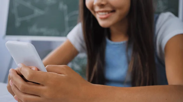 Cropped view of kid chatting while holding smartphone — Stock Photo