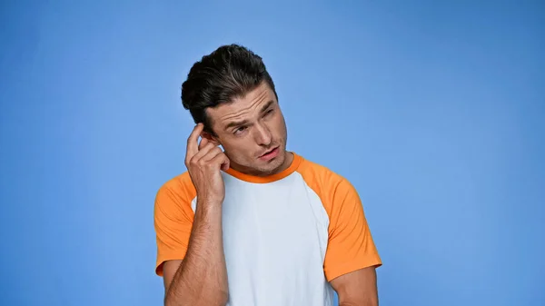 Hombre reflexivo rascarse la cabeza y mirar hacia otro lado aislado en azul - foto de stock