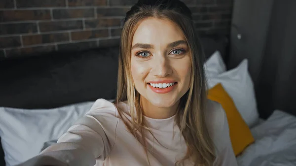 Feliz joven mujer sonriendo a la cámara en la habitación de hotel - foto de stock