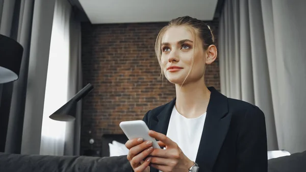 Businesswoman in formal wear holding smartphone in hotel — Stock Photo