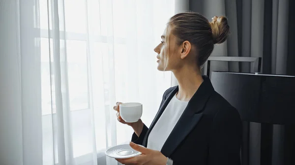 Empresária em terno segurando xícara de café no hotel — Fotografia de Stock