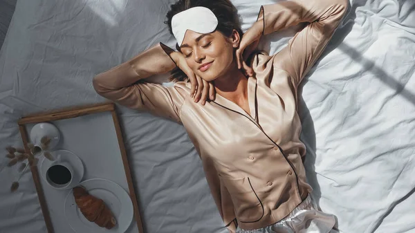 Top view of smiling woman stretching in bed near tray with tasty breakfast — Stock Photo