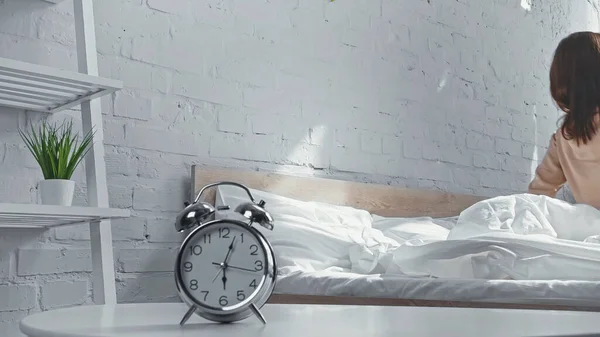 Retro alarm clock near woman getting up from bed in morning — Stock Photo