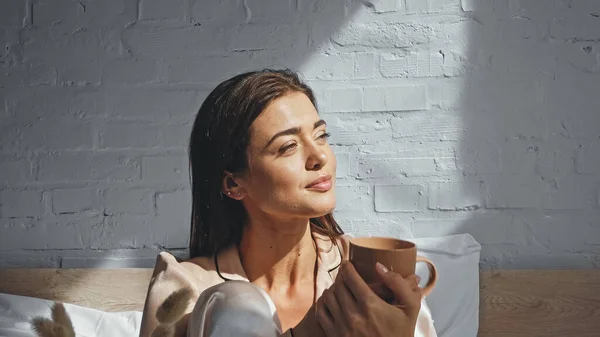 Happy woman holding cup of tea and looking away — Stock Photo