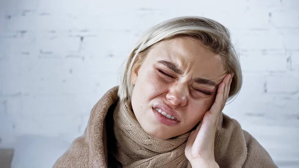 Donna malata accigliata con gli occhi chiusi mentre soffre di mal di testa in camera da letto — Foto stock