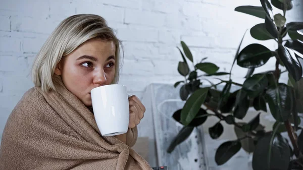 Mulher loira doente beber chá quente enquanto assiste tv no quarto — Fotografia de Stock