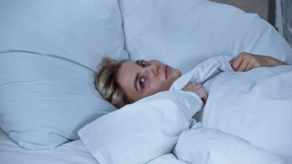 Donna malata distogliendo lo sguardo mentre sdraiato nel letto sotto coperta calda — Foto stock