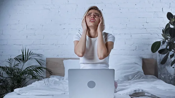 Young teleworker looking up while suffering from migraine in bedroom — Stock Photo