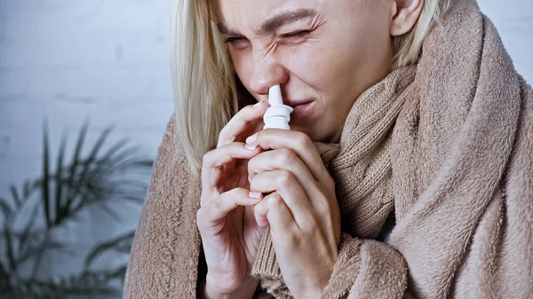 Jovem mulher doente franzindo a testa ao usar spray nasal — Fotografia de Stock