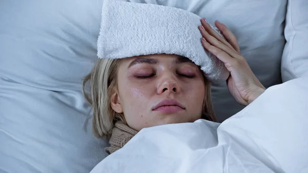 Mulher doente deitado com os olhos fechados e comprimir tocando na testa — Fotografia de Stock