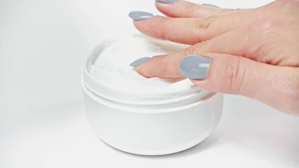 Cropped view of woman applying cosmetic cream from container on white — Stock Photo