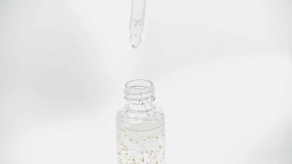 Close up of pipette above glass bottle with essential oil on white — Stock Photo