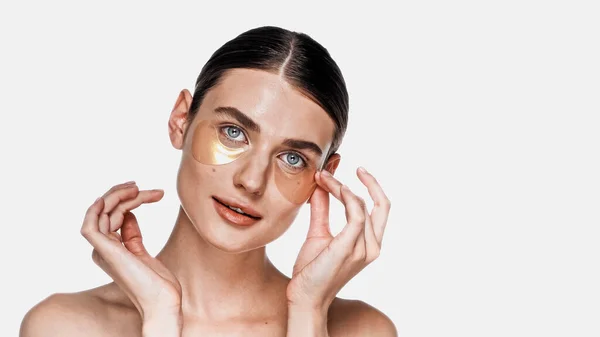 Mujer que aplica parches debajo de los ojos aislados en blanco — Stock Photo