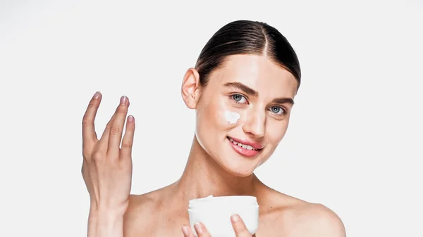 Happy woman holding jar and applying cosmetic cream isolated on white — Stock Photo