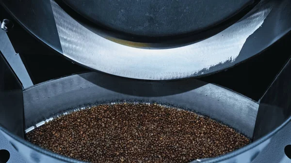 Vista de ángulo alto de granos de café tostados en la máquina de tostado moderna - foto de stock