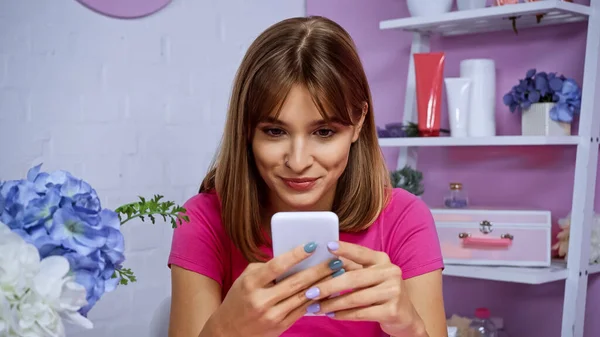 Alegre joven mujer con piercing mensajes de texto en el teléfono inteligente - foto de stock