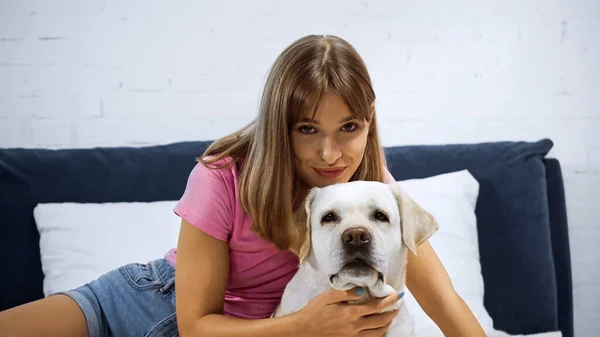 Young happy woman looking at camera near golden retriever — Stock Photo