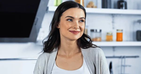 Mujer morena mirando hacia otro lado y sonriendo en la cocina — Stock Photo