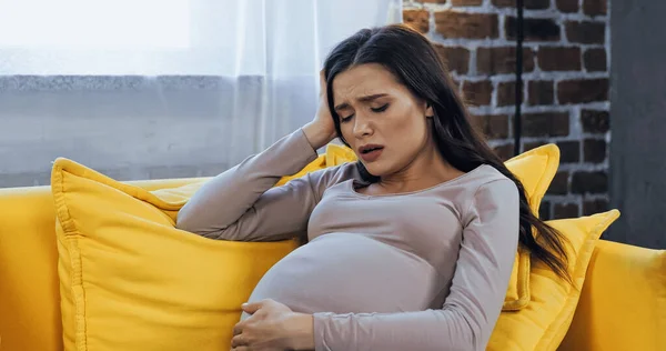 Mulher grávida perturbada sentada no sofá — Fotografia de Stock