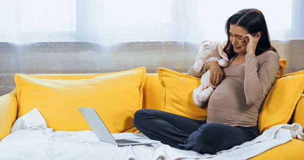 Schwangere mit Stofftier weint in der Nähe von Laptop — Stockfoto