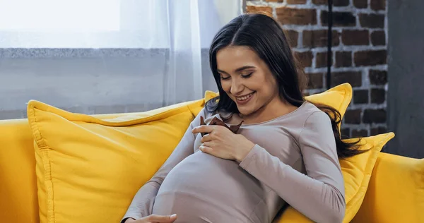 Cheerful pregnant woman holding cupcake at home — Stock Photo