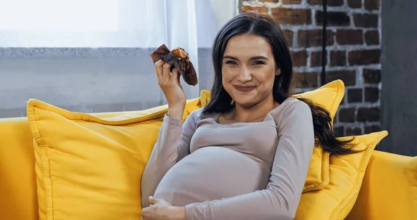 Cheerful pregnant woman holding cupcake at home — Stock Photo