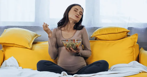 Mulher grávida agradável comer salada fresca na sala de estar — Fotografia de Stock