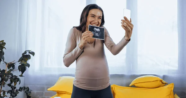 Mulher grávida alegre mostrando ultra-som do bebê durante a chamada de vídeo — Fotografia de Stock