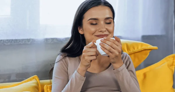 Smiling woman with closed eyes holding coffee cup — Stock Photo